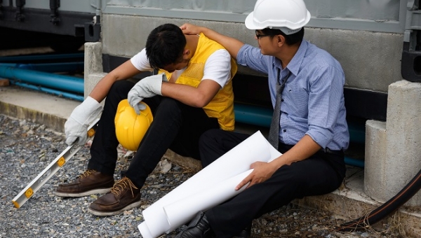 Sad Asian unemployed young foreman cry while Senior engineer manager comfort and cheer up at construction site. bad economy situation forces to layoff employees.